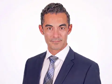 Michael Uvalle, founding attorney of LAWBOSS, Uvalle Law Firm, PLLC, in a navy suit and striped tie against a white studio background