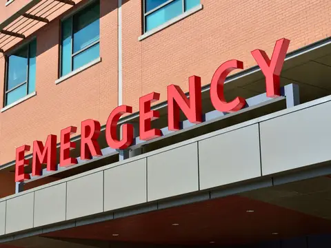 Red EMERGENCY letters over a hospital entrance canopy on a brick building