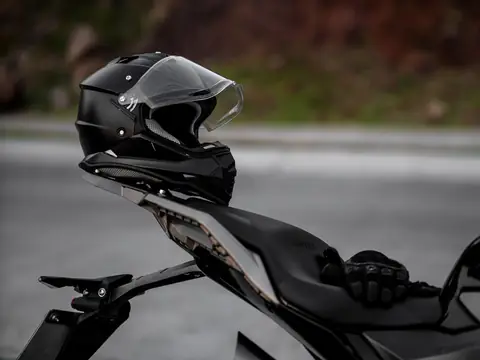 A black full-face motorcycle helmet resting on the seat of a parked black sport bike